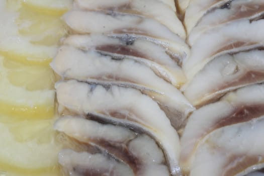 Fine slices of a herring in oil with finely cut slices of a lemon 