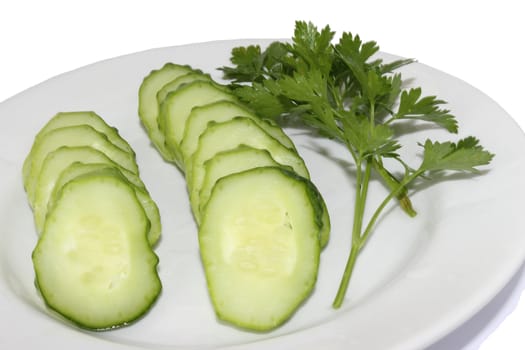 It is thin the cut slices of a cucumber and small branches of a parsley on a plate on a white background