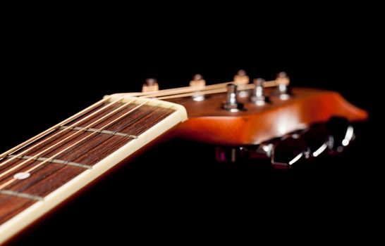 Macro shot down the fretboard of acoustic guitar with shallow depth of field