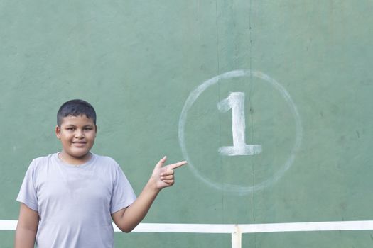 Boy action pointing number one at tennis practice wall