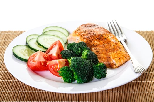 A dinner of baked salmon, broccoli, tomatoes and cucumber