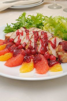 Sliced ​​baked fillet with cranberry sauce in lettuce leaves with orange and grapefruit