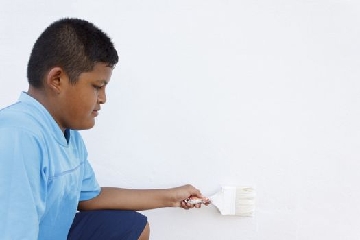 Thai boy painting the wall white with a paint brush