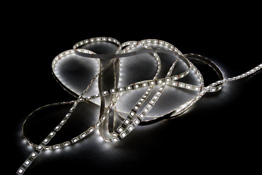 white led strip with a glue layer, background in the dark, illuminated by strip