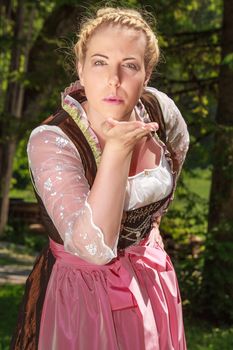 Bavarian girl in festive costumes handing out kisses