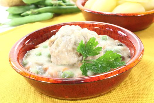 cooked meatballs in a white sauce with capers, garlic and parsley