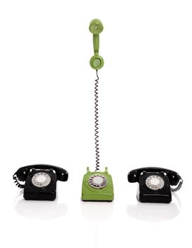Green phone ringing in the midle of two black phones, isolated on white background