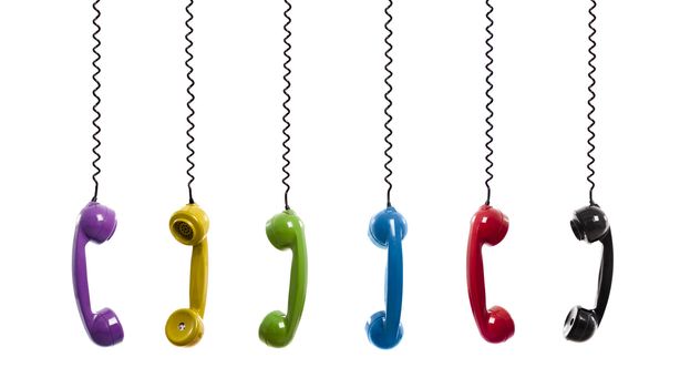 Multi colored handset pieces suspended by the phone cord, isolated on white background