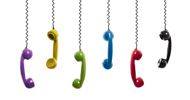 Multi colored handset pieces suspended by the phone cord, isolated on white background