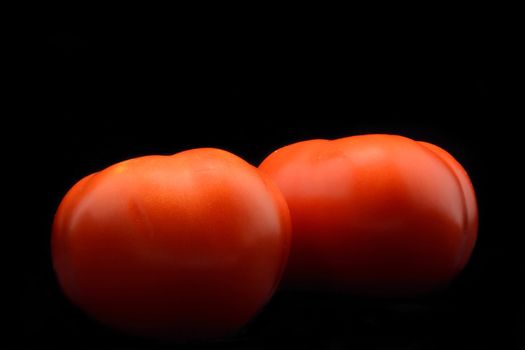 Fresh tomato couple isolated over black background