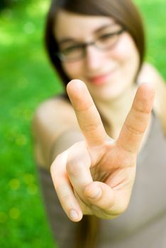 smiling young woman making victory gesture towards the camera