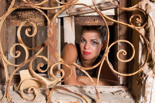 Portrait of a woman looking out of the window of a ruin