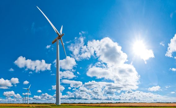 wind turbines in rural area on a field in front of a beautiful sky