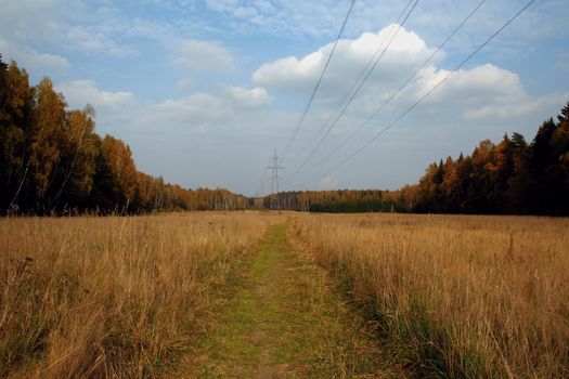 sun and clouds over rural road, power transmission line and the forest