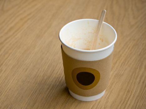 White Empty paper cup of coffee with safety cardboard collar on a wooden table