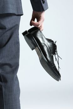 businessman holding the shoes in hand, close up