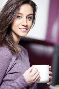 Beautiful young  woman having coffee while at the kitchen