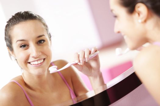 young woman in bathroom cleaning her teeth 