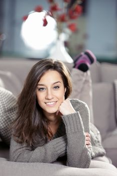 Portrait of a beautiful young woman lying on couch