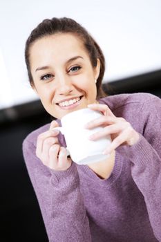 Beautiful young  woman having coffee while at the kitchen