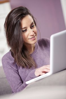 portrait of young woman on the sofa using laptop