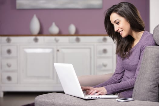 portrait of young woman on the sofa using laptop