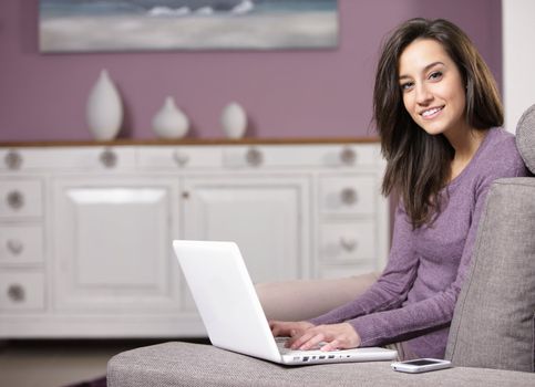 portrait of young woman on the sofa using laptop