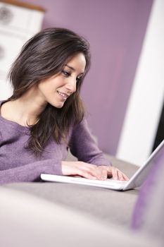 portrait of young woman on the sofa using laptop