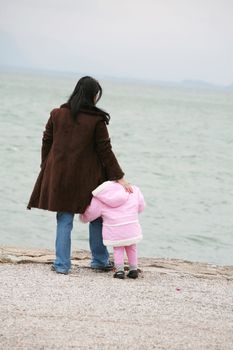 Mother and daughter looking the sea on winter