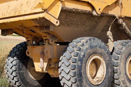 Large yellow mining truck with huge tires at construction site