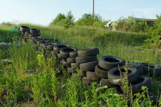 Fence made ??of old used tires in meadow. Natural pollution.