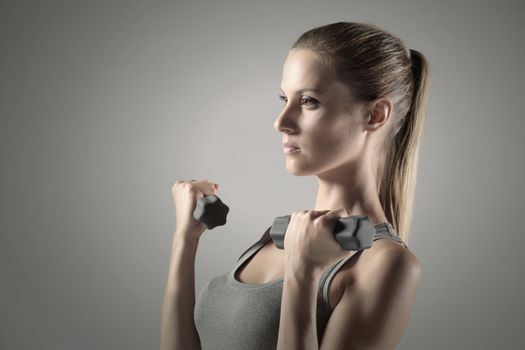 A beautiful woman raises with dumbbells 