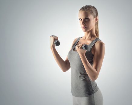 A beautiful woman raises with dumbbells 