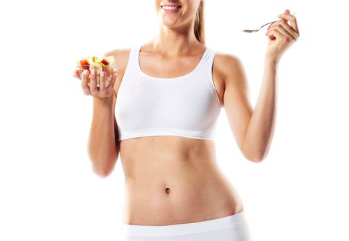 Fit young woman eating fruit salad