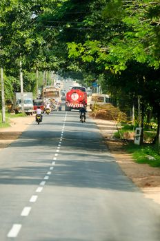 Habarana, Sri Lanka - December 6, 2011: Intensive traffic on a narrow asian street with regular bus covered by drawings, motobikes and car.