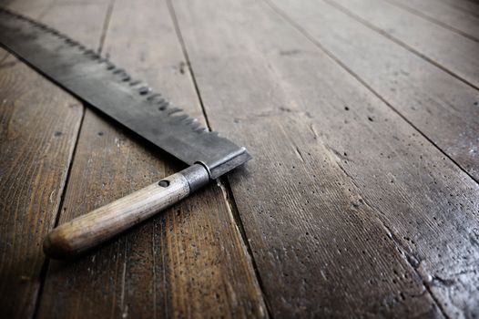 a old saw of a woodcutter is leaning against the old wood floor. Copy space