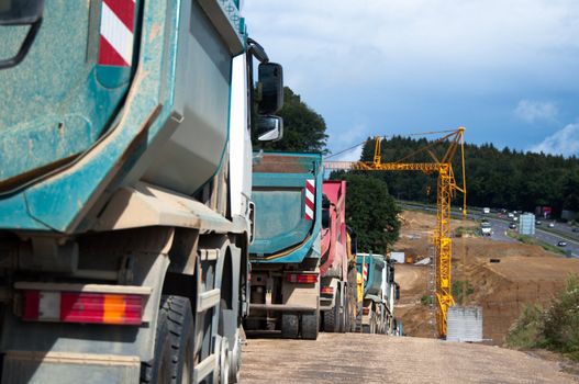 Row of dum trucks being parked at a highway construction site in Germany