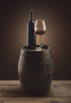 red wine bottle and wine glass on wooden barrel