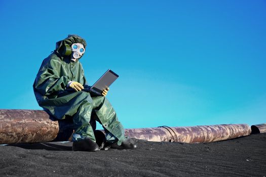 A scientist working with a laptop on a chemically contaminated area