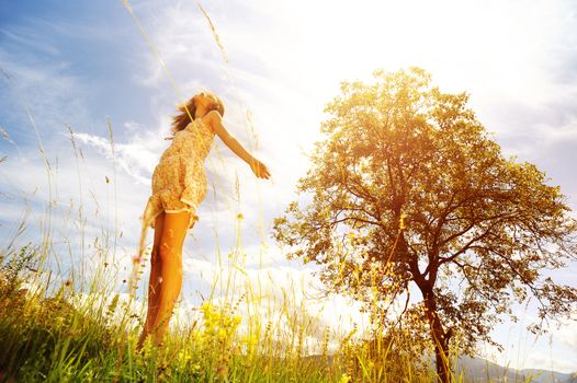 Beautiful woman  in the midst of a green lawn, she looks at the sky, so carefree