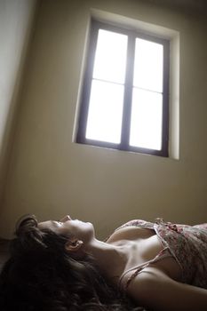 a girl lying on the floor looking at a bright window