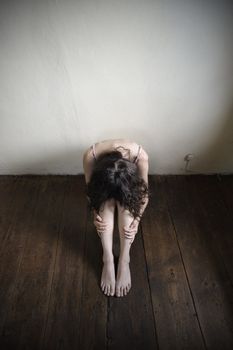 a desperate young woman is sitting on an old wooden floor. top view