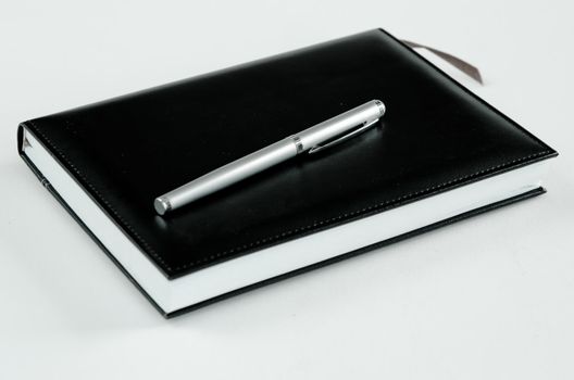 black note book and pen for records on white 