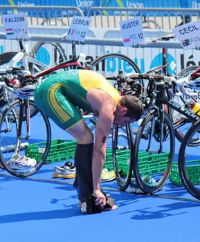 Man athlet removing his clothes to start bicycling at transition space at the International Geneva Triathlon, on July 22, 2012 in Geneva, Switzerland.