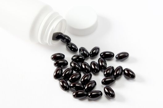 Pills spilling out of  pill bottle on white background