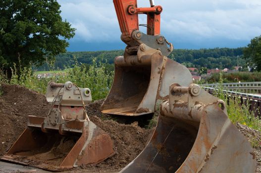 Excavator on construction site with different sized shovels