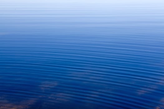 Abstract background dark blue water ripples fading to light blue.