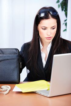 Pretty young woman in office with bag and computer