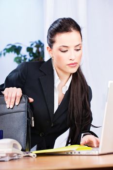 Sensual brunette woman working on notebook in office