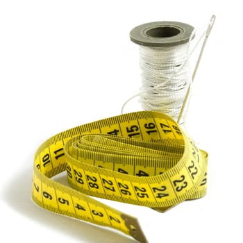 A bobbin with needle , white thread  and a  tape-measure, isolated on white background

